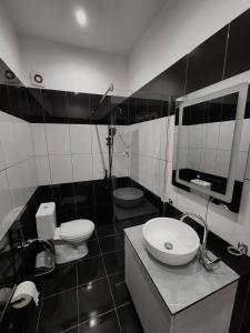 Un baño con lavabo, inodoro y espejo. en Aura Hotel, en Durrës