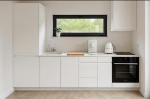 a white kitchen with a sink and a window at NATURA APARTAMENTY Era in Ulinia +22 photos