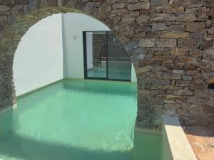 an indoor pool with a stone wall and blue water at GEA & HYDOR Private Residencies Antiparos in Agios Georgios