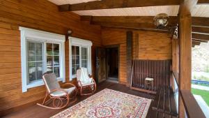a porch of a cabin with two chairs and a rug at Риддер Тайга- Ridder Taiga 