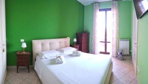 a bedroom with a white bed with green walls and a window at Casa Prinz in Marotta +3 photos