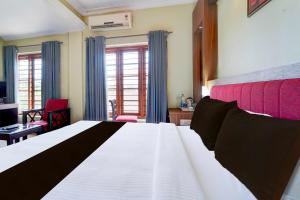 Un dormitorio con una gran cama blanca con cabecero rojo. en Collection O MG Road Trivandrum, en Trivandrum