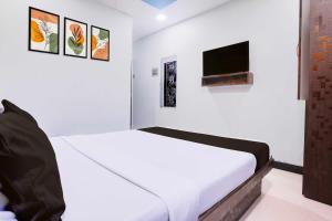 a white bedroom with a bed and a flat screen tv at Hotel O Asalpha near International Airport in Mumbai