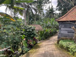 un chemin en briques dans un jardin planté d'arbres et de plantes dans l'établissement Cabin D Bendul and Warung, à Tabanan