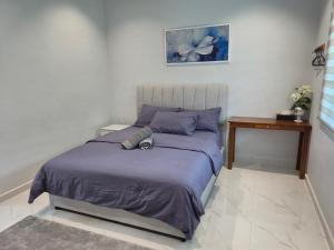 a bedroom with a bed with purple sheets and a table at NAR Kampung Studio in Bayan Lepas
