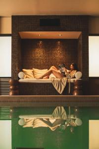 una mujer sentada en una cama leyendo un libro en Les Lodges Sainte-Victoire Hotel & Spa, en Aix-en-Provence