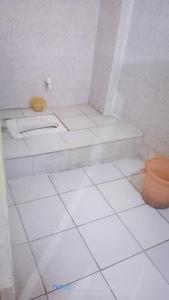 a white tiled bathroom with a sink and a toilet at Hotel Shristy Residency in Dhanbād