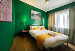 a green bedroom with a bed and a green wall at & Art Motel in Tootgarook