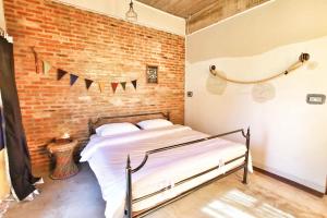 a bedroom with a bed and a brick wall at Above The Sea Maesariang in Mae Sariang