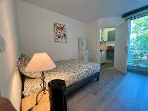 a bedroom with a bed and a lamp and a kitchen at Relax-Parc des expos-Wifi by La clé des expos in Vanves