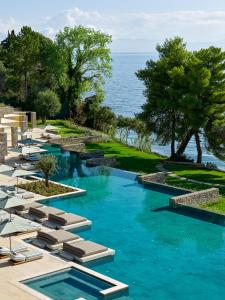 a pool with lounge chairs and the ocean in the background at Avali, Mar-Bella Collection in Agios Ioannis Peristeron