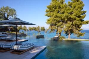 a swimming pool with lounge chairs and an umbrella at Avali, Mar-Bella Collection in Agios Ioannis Peristeron +48 photos