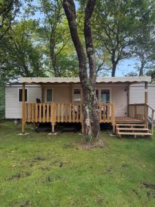 a small house with a porch and a tree at Mobil home B1Bis La Pointe LB in Capbreton