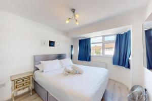 a bedroom with a large white bed with blue curtains at 3 Bed Home - 10 Min Walk to Mill Hill Tube in Hendon