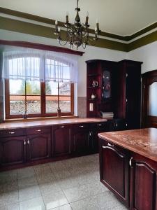 a kitchen with wooden cabinets and a large window at Rezydencja Gołębiówka Mazury in Targowo