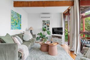 a living room with a couch and a tv at 'The Aerie' Bushland A-frame Escape with Retro Charm in Katoomba
