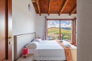 una camera da letto con un letto e una grande finestra di Corte di Gallura a Budoni Altre 30 foto