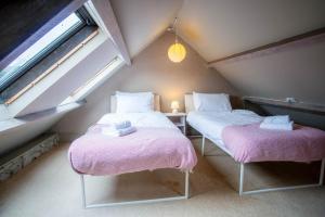 two beds in a attic room with pink sheets at Bwthyn Berwig - 3 Bedroom Cottage - Llanrhidian in Swansea