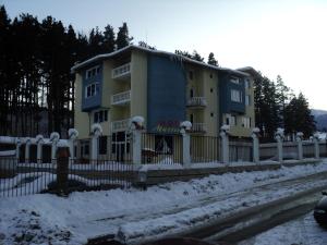a building with a fence in the snow at Hotel Materhorn in Razlog