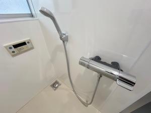 a shower in a bathroom with a hose on the wall at 若葉コーポ103 in Fukuoka +5 photos
