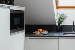 a kitchen with a plate of bread and a microwave at Coco Chanel Boutique Apartment by Goodnite cz in Brno