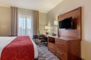a hotel room with a bed and a desk with a television at Comfort Suites in Rolla