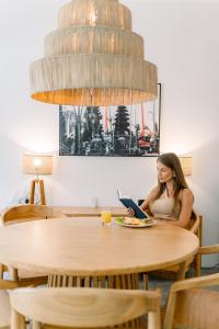 une femme assise à une table avec un ordinateur portable dans l'établissement Villa Castello di Quassolo, à Canggu