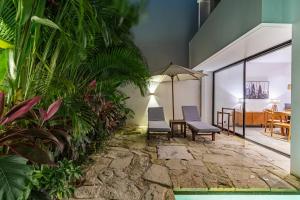 un patio avec deux chaises et une table et quelques plantes dans l'établissement Villa Castello di Quassolo, à Canggu