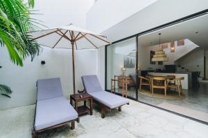 un salon avec deux chaises et un parasol dans l'établissement Villa Castello di Quassolo, à Canggu