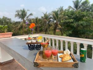 a tray of food and drinks on a table on a balcony at Casa Nauka in Colva