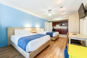 a hotel room with two beds and a kitchen at Ramada by Wyndham Flamingo Water Park in Kissimmee