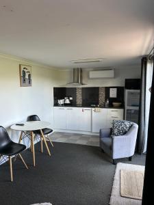 King River Caravan Park في Whitfield: مطبخ مع خزائن بيضاء وطاولة وكراسي