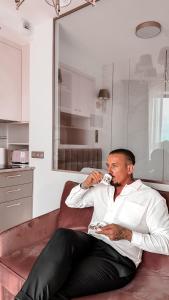 a man laying on a bed brushing his teeth at Pratum Pink&Blue Apartament Glamour z widokiem na jezioro i wanną in Mikołajki