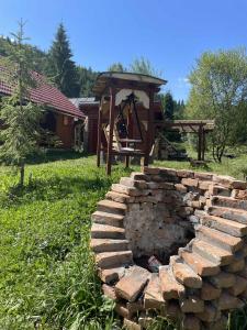 a brick fire pit in a yard with a playground at Csanodi erdei ház in Gheorgheni +6 photos