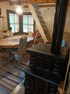 a living room with a stove and a table and chairs at Csanodi erdei ház in Gheorgheni