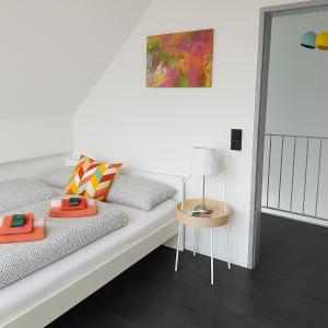 Ferienwohnung Maisonette am See في Markelfingen: أريكة بيضاء مع وسائد وطاولة مع مصباح