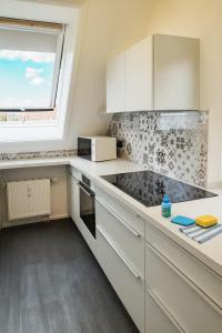 Ferienwohnung Maisonette am See في Markelfingen: مطبخ بخزائن بيضاء ونافذة +صورتان