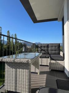 a balcony with a glass table and wicker chairs at BlackDEER Apartment Liptov in Liptovský Mikuláš