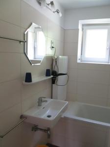 La salle de bains est pourvue d'un lavabo, d'une baignoire et d'un miroir. dans l'établissement Gästehaus Santer, à Rothenthurn