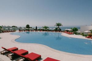 a large swimming pool with red chairs and umbrellas at Masana Algarve in Albufeira