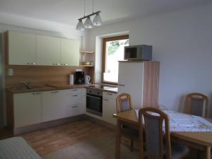 Una cocina con una mesa y un refrigerador blanco. en Gästehaus Santer, en Rothenthurn