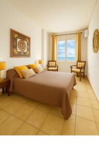 a bedroom with a large bed with two chairs and a window at Vue exceptionnelle début Cap Corse La Pier Noire in San-Martino-di-Lota