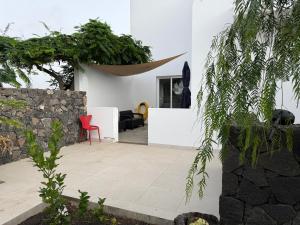 a patio with a red chair in a white house at Finca Seño Donato Lomo La Santa in Tinajo