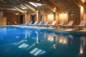 a swimming pool with chairs in a building at Hotel Beauregard in La Clusaz