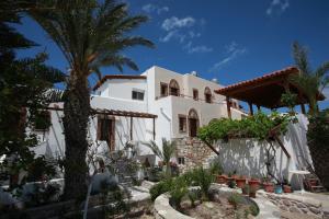 a white house with a palm tree and some plants at Panorama Studios in Kefalos