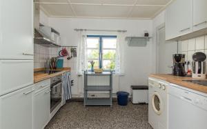 Una cocina con gabinetes blancos y una ventana. en Luisenhof, en Süderhöft