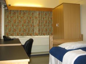 Habitación con cama, escritorio y cortina. en University of Toronto - New College Residence - Wilson Hall Residence, en Toronto