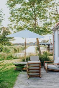an umbrella and chairs on a wooden deck at Villa aan het water met hottub in Dokkum