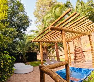 a wooden pergola with two chairs and a pool at Casa Romantica in Los Palmitos