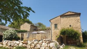 a building with an umbrella and a stone wall at Mas des Pelissiers Gîte in Sabran